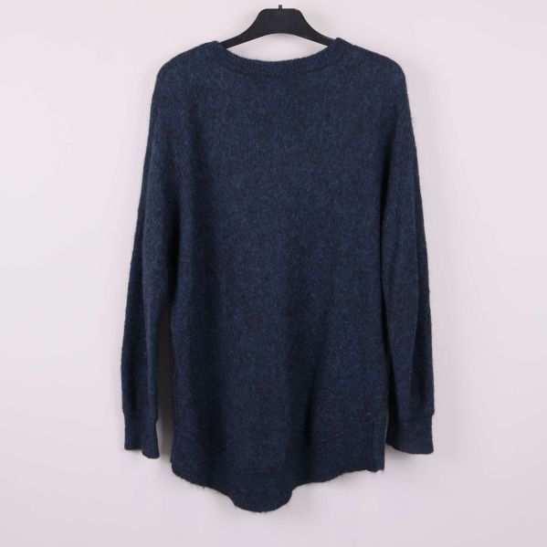 Stickad blå tröja sedd bakifrån hänger på galge