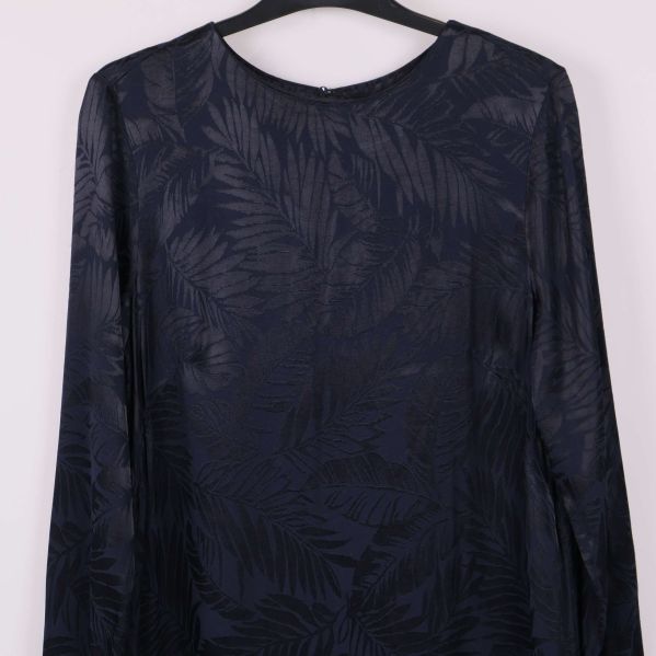 Närbild på överdelen av mörkblå mönstrad klänning