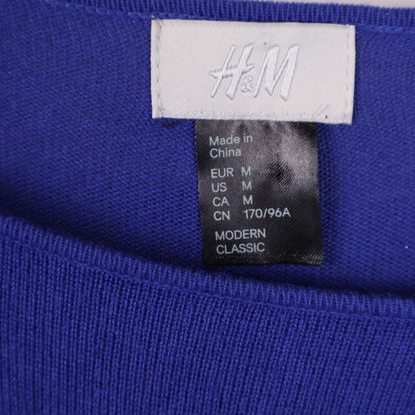 Närbild av H&M-logotyp och storleksetikett i klänningen