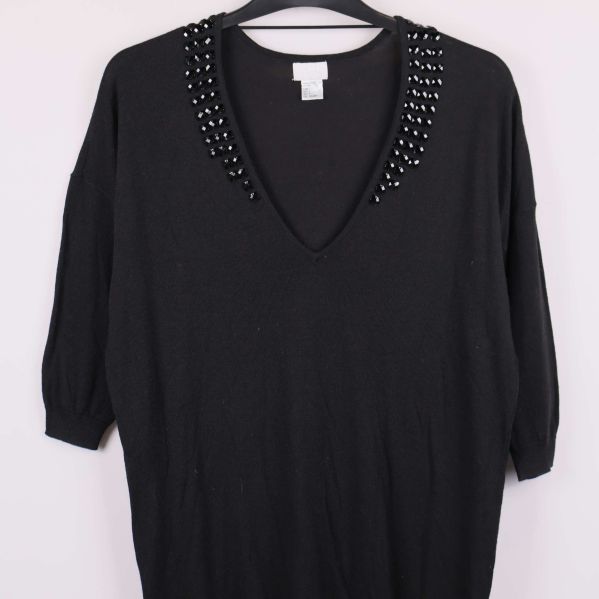 Svart tröja med dekorativa stenar visar v-ringning