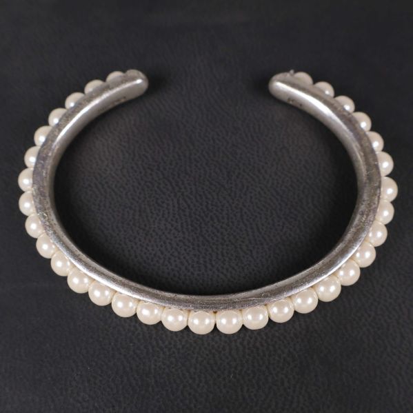 Närbild på silverfärgat armband med pärlor