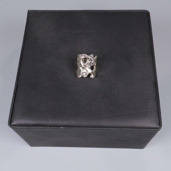 Silverfärgad ring placerad på svart fyrkantig ask