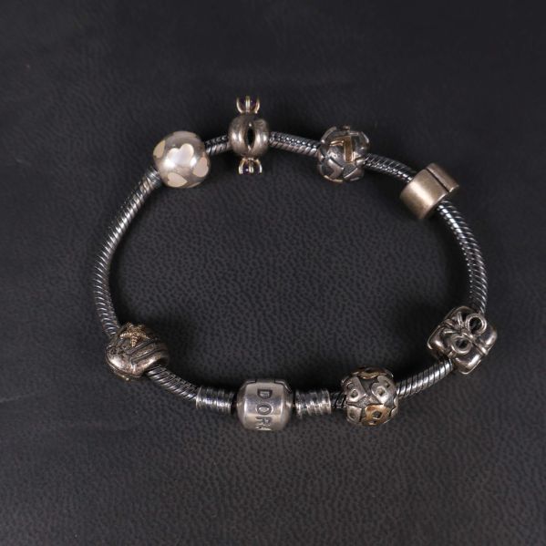 Pandora armband med berlocker liggande på svart underlag