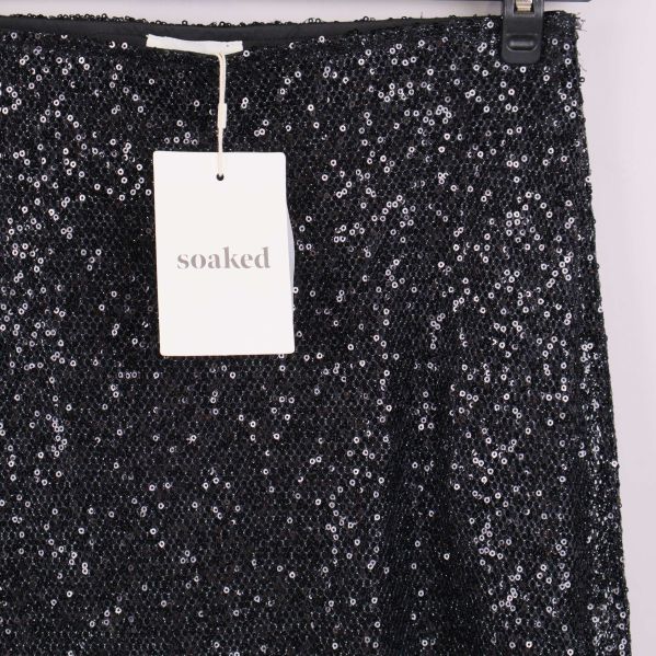 Detaljbild av överdelen på svart paljettkjol med Soaked-tagg