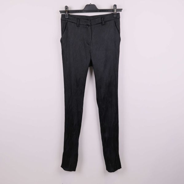 Svarta byxor med struktur hängande mot ljus bakgrund