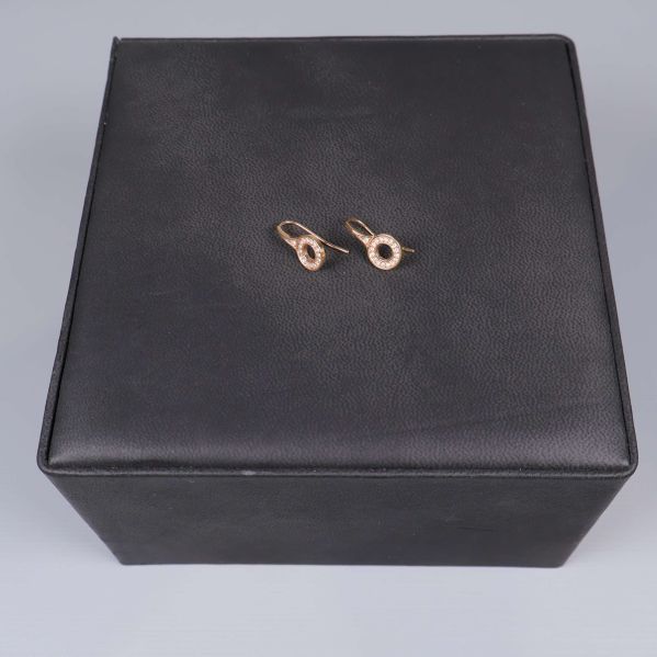 Ett par roséguldsörhängen på svart bakgrund