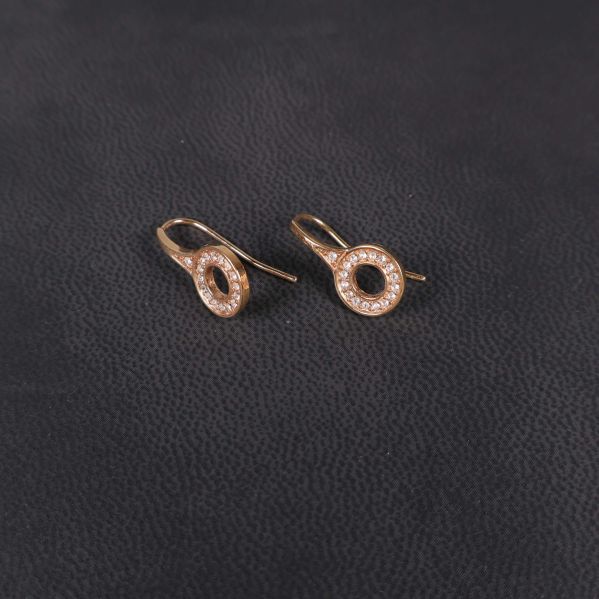 Närbild på två örhängen i roséguld med stenar