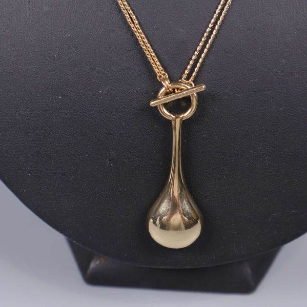 Närbild på halsbandets droppformade hänge i metall