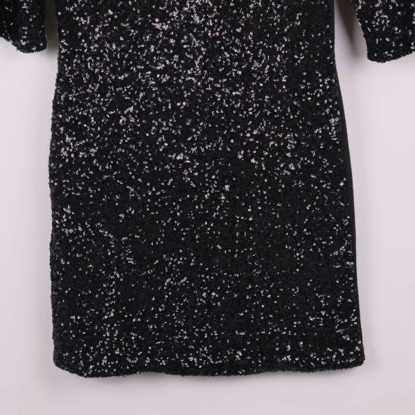 Nedre delen av svart klänning täckt av paljetter
