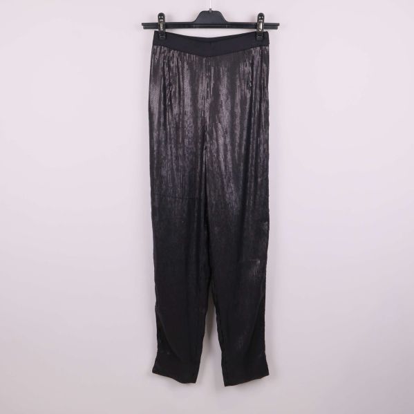 Svarta paljettbyxor hänger på galge mot ljus bakgrund