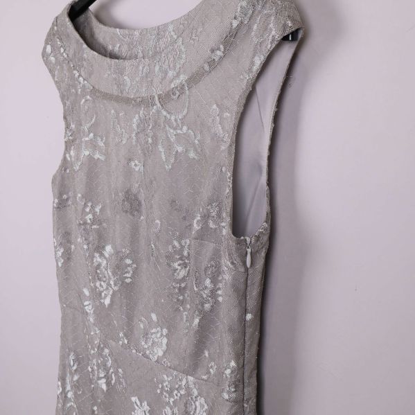 Sned närbild på axel och överdel av silverfärgad spetsklänning