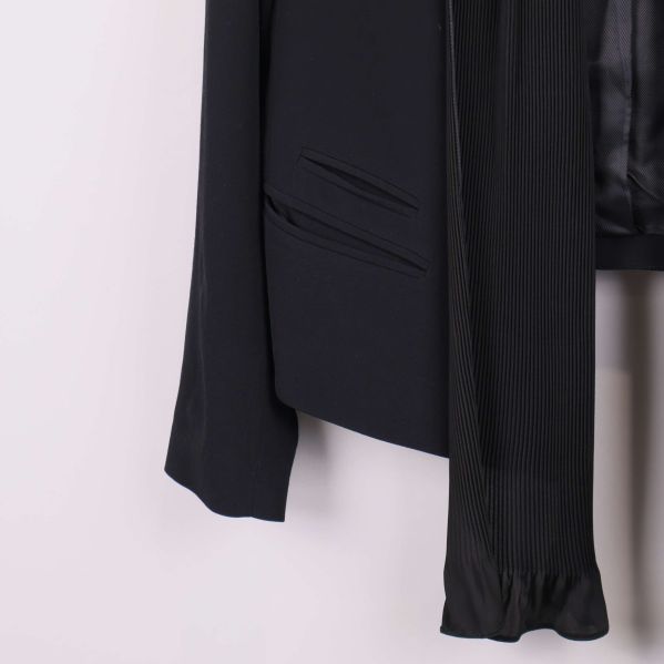 Närbild på ficka och plisserad scarfdetalj på kavaj