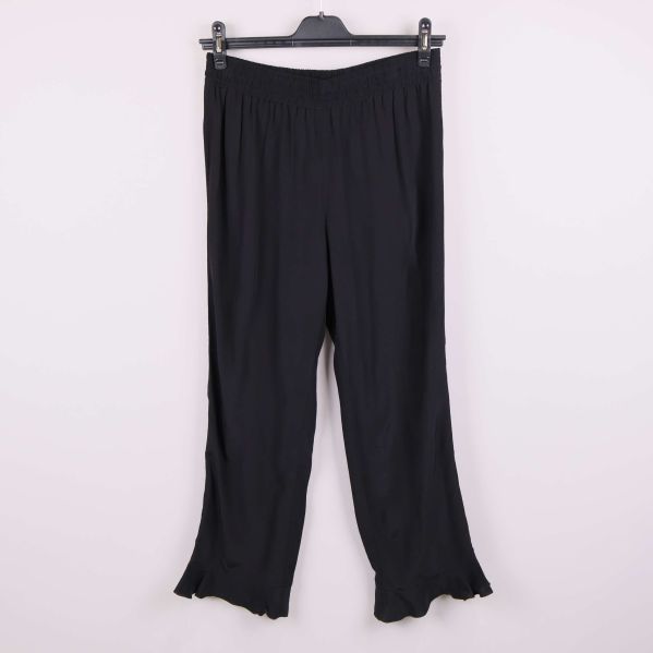 Vida svarta byxor hängande på galge med volangkant nertill