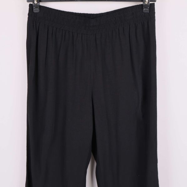 Närbild på midja och byxben för svarta vida byxor