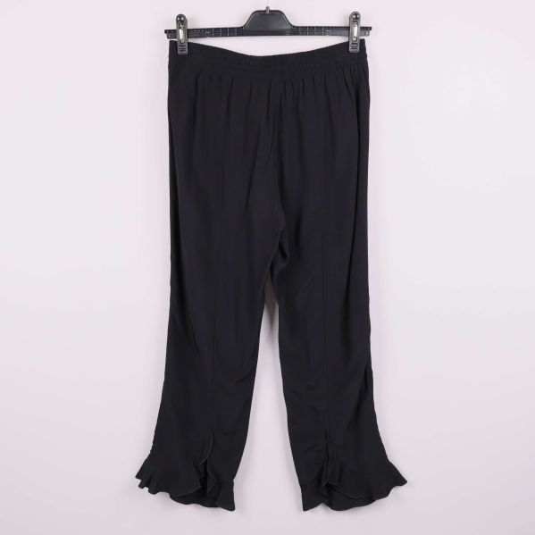 Baksidan av svarta vida byxor med volangdetalj vid foten