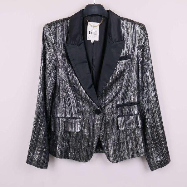 Kavaj med glittrande yta och svarta detaljer på galge