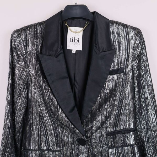 Framstycke av glittrig kavaj visar fickor och knäppning