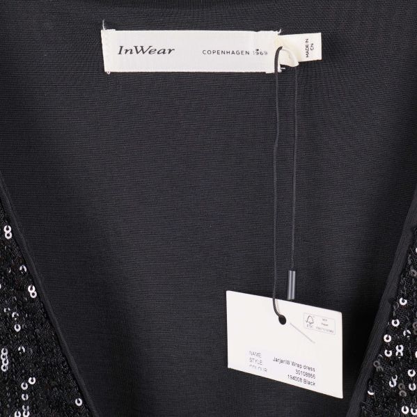 Närbild av InWear-märkesetikett och prislapp i klänningens ringning