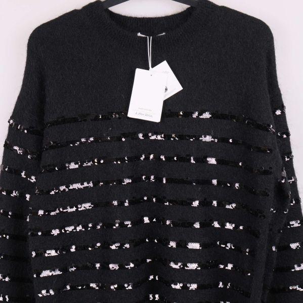 Närbild på tröjans övre del med paljettränder och etikett