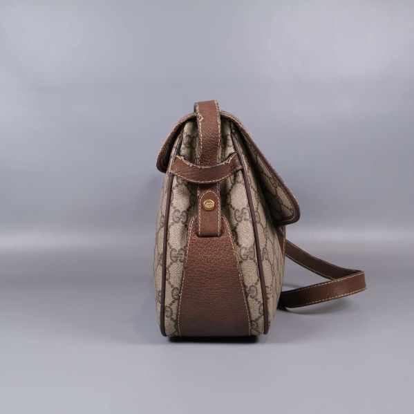 Sidan av väskan med bruna läderdetaljer och axelrem