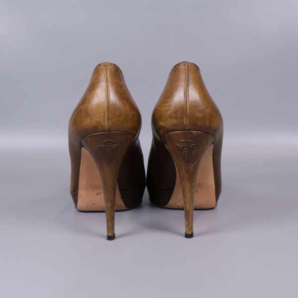 Bruna pumps sedda bakifrån med präglad logotyp