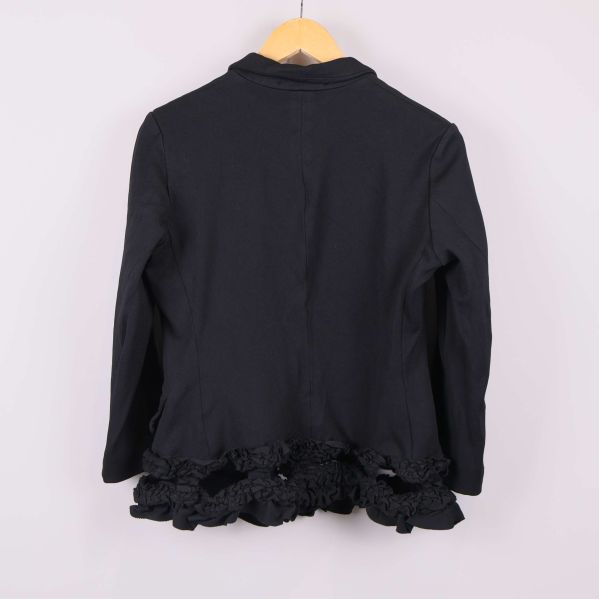 Baksidan på svart kavaj med volang längs fållen