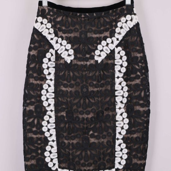 Detaljbild på överdelen av svart kjol med vita broderier