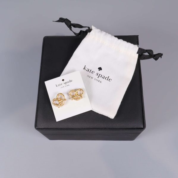 Guldfärgade hjärtformade örhängen på Kate Spade-kort med tygpåse