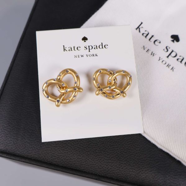 Närbild på guldfärgade örhängen i hjärtform och tygpåse