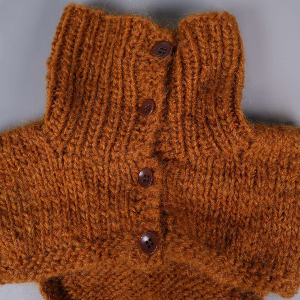 Närbild på knapprad på orange stickad halskrage