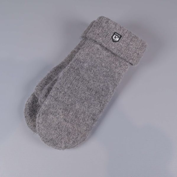 Grå stickade tumvantar med uppvikt mudd liggande på grå bakgrund