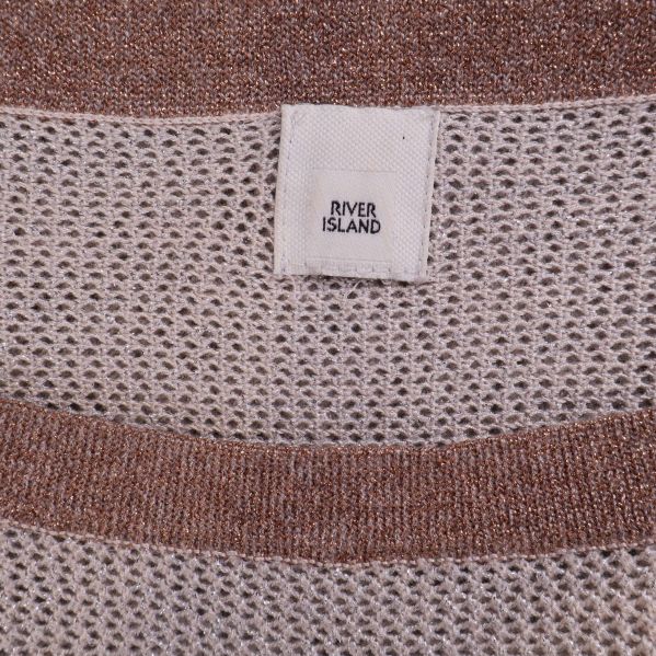 Närbild på River Island-märke och brun halskant på stickad tröja