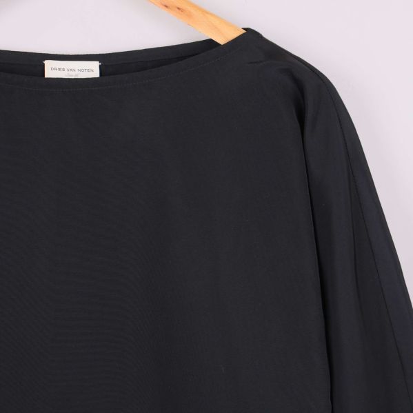 Närbild på halsringning och axel med blusens struktur synlig