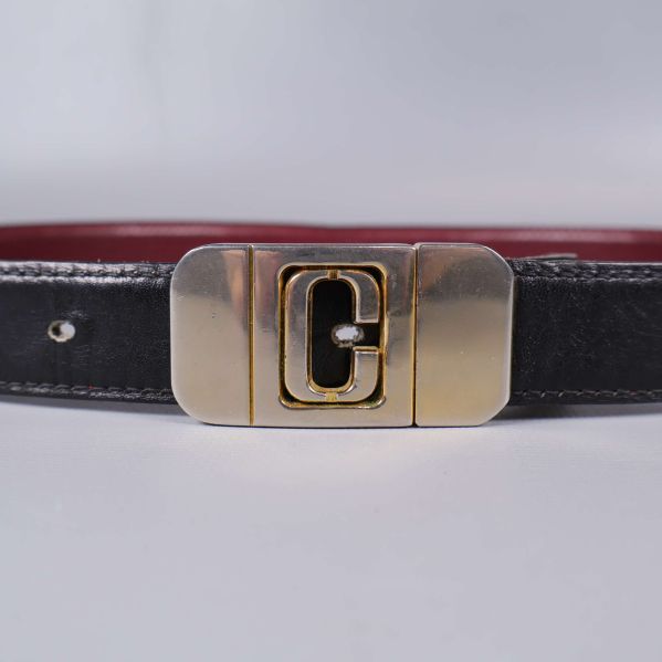 Närbild på bältets mässingsspänne med C-detalj