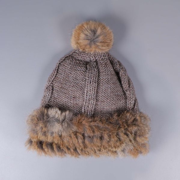 Baksidan av beige stickad mössa med pälsboll och fuskpäls