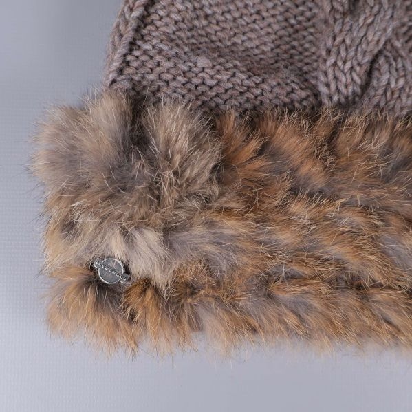 Närbild på mössans fuskpäls och metallmärke