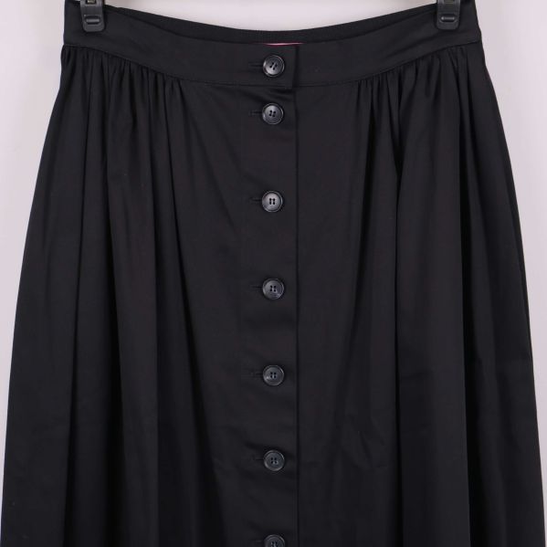 Närbild på överdelen av svart kjol med knappar