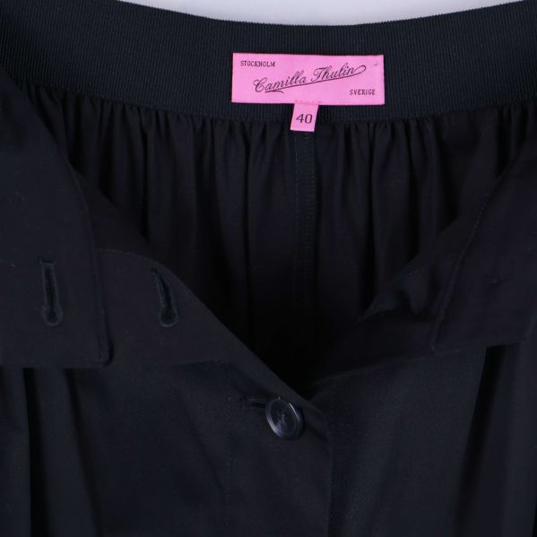 Närbild på midjan och etikett med storlek på svart kjol