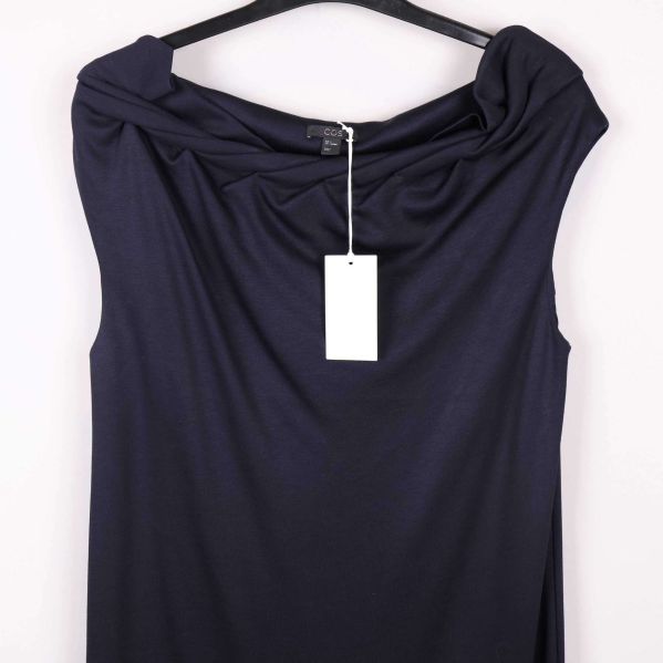 Detalj draperad halsringning och etikett