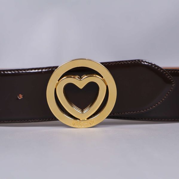 Närbild på hjärtspänne i guld på läderbälte