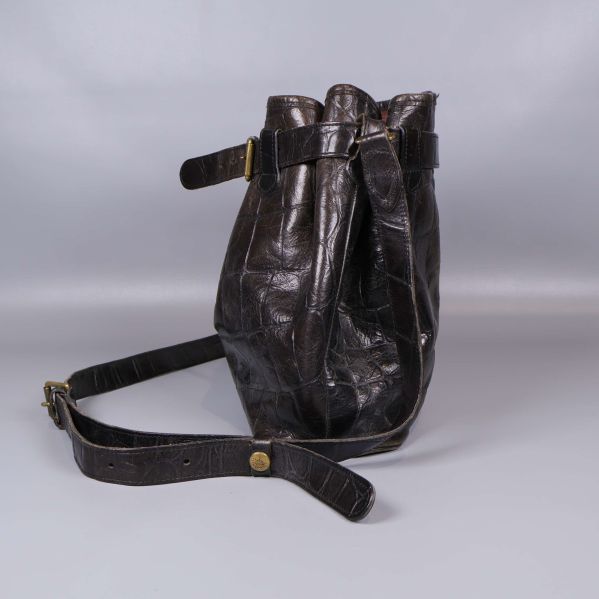 Väskans ena sida med präglat skinn och rem synlig