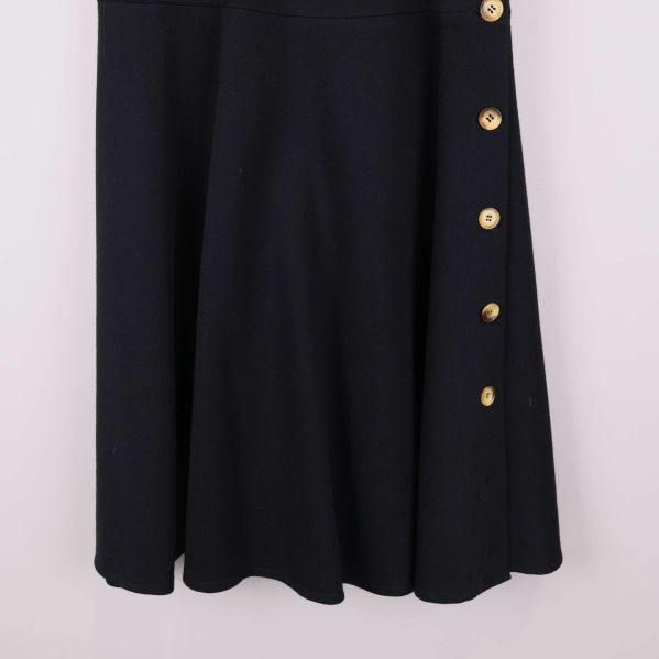 Nedre delen av svart kjol med knappar, närbild