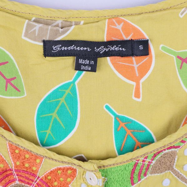 Närbild på klänningens etikett och bladmönster