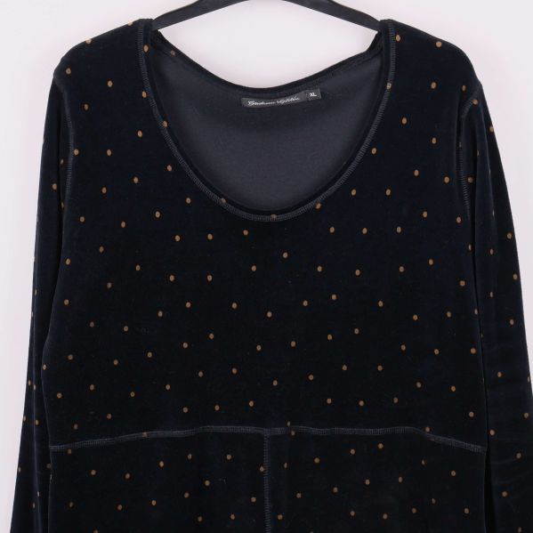 Närbild på klänningens halsringning och prickigt tyg