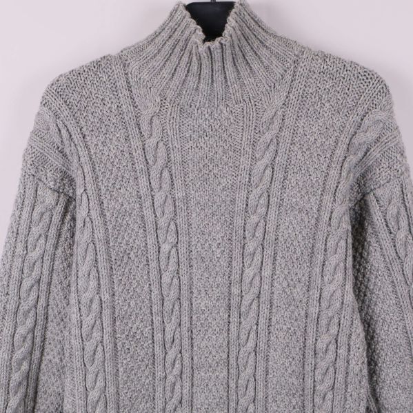 Närbild på den höga kragen och kabelstickat mönster