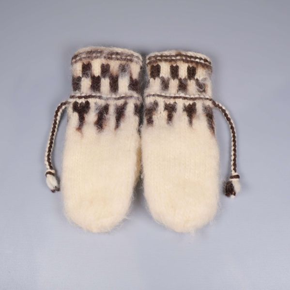 Baksidan av stickade tumvantar med mönster och knytband