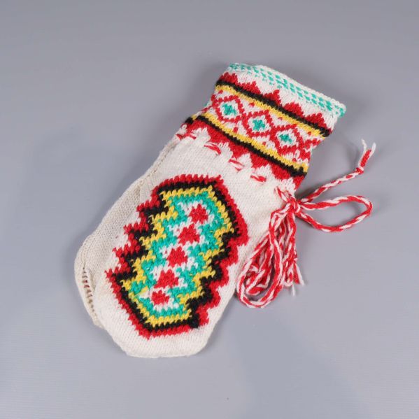 En stickad tumvante med flerfärgat mönster och rödvit snodd