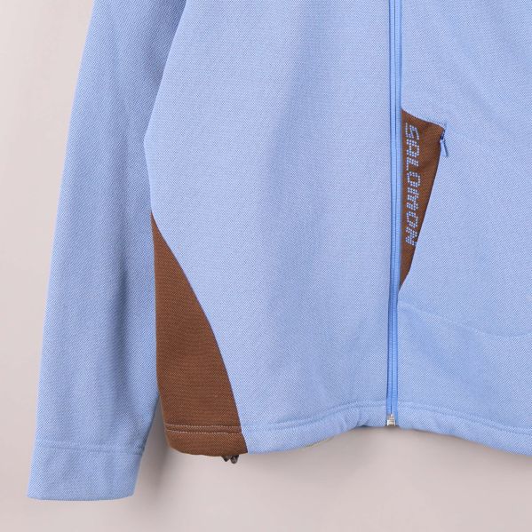 Närbild på vänster ficka med brunt tyg och Salomon-tryck