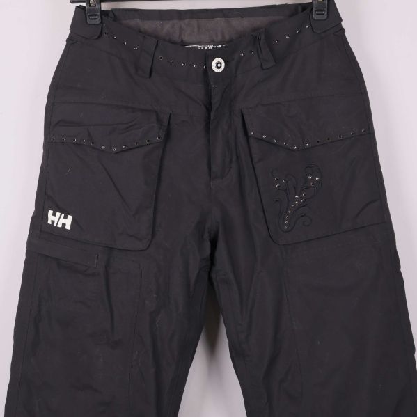 Närbild av framfickor, knapp och dekorativa detaljer