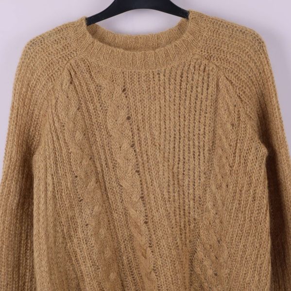 Närbild av flätmönster på stickad tröja med rund hals